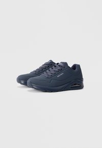 Navy blue athletic sneakers with a textured upper, perforations for breathability, cushioned sole, and visible air pocket in the heel area.
