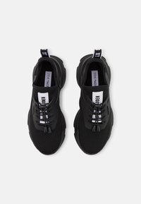 Schwarze Sportschuhe aus atmungsaktivem Mesh mit strukturiertem Design. Verfügt über elastische Schnürsenkel, einen markierten Zuglasche und eine dicke Sohle.