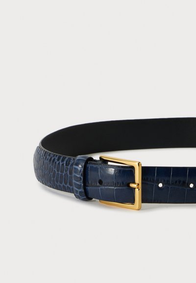 Ceinture en cuir texturé bleu marine avec boucle rectangulaire dorée sur un fond clair uni.