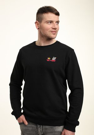 Sort bomulds-sweatshirt med lange ærmer, ribbede manchetter og kant. Har farvede broderede Tom og Jerry-figurer på brystet.