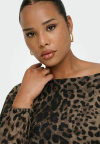Top con stampa leopardata realizzato in un morbido tessuto testurizzato nei toni del marrone e del nero, con scollatura ampia e maniche arricciate. Orecchini a cerchio dorati.