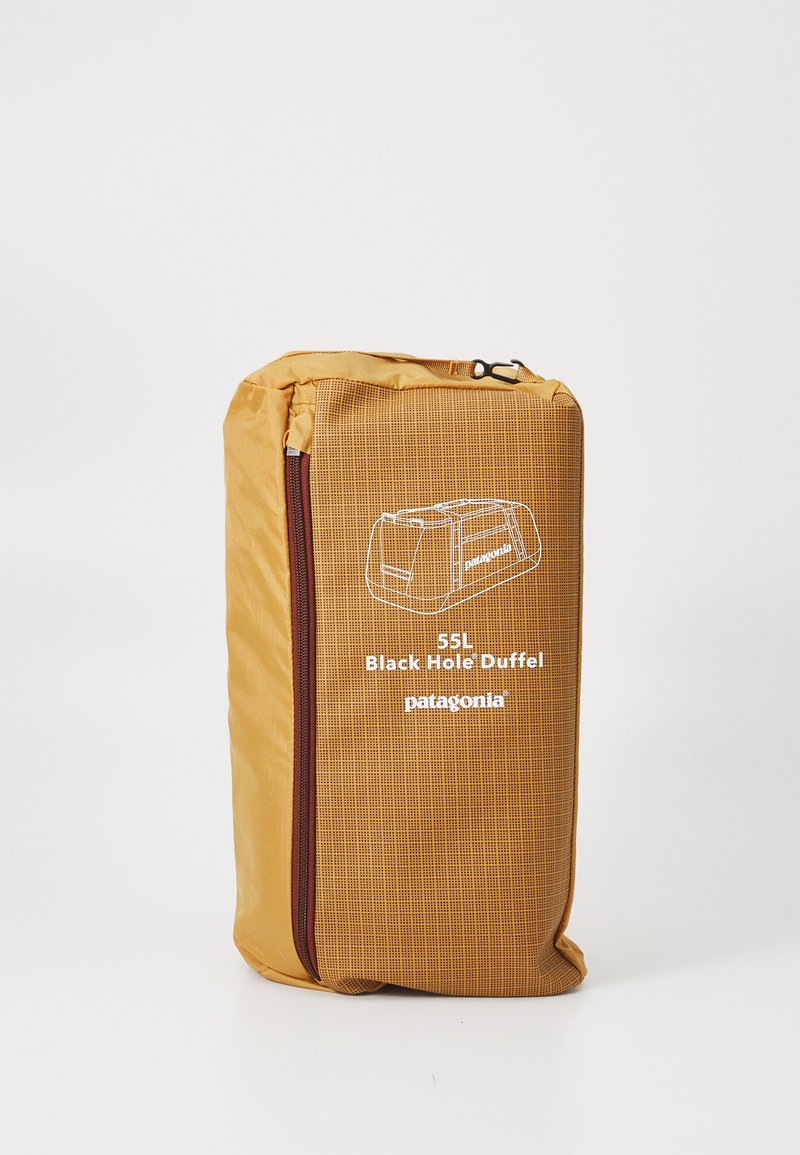 Kompakts dzeltenais iepakojuma kubs ar rāvējslēdzēju un drukātu balto ilustrāciju un tekstu "55L Black Hole Duffel Patagonia."