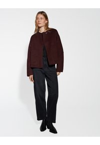Burgundy wool blend cropped jacket with a round neckline and front pockets, paired with black high-waisted trousers and black ankle boots.