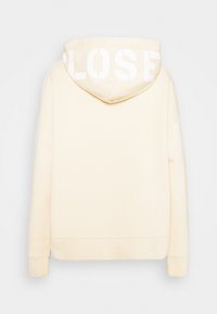 Sweat à capuche couleur crème à manches longues vu de dos, avec le mot "LOST" en grandes lettres blanches sur la capuche.