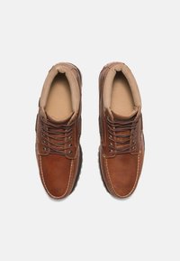 Chaussures en cuir marron avec un bout rond, un col rembourré et un devant à lacets. Présentent des accents cousus et une semelle en caoutchouc pour une bonne adhérence.