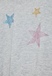 Szürke, könnyű póló, négy színes csillagmintával kék, sárga, rózsaszín és ezüst strasszokkal, a "Designed" felirattal fémszerű írásban.