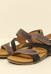 Hnědé kožené sandály s překříženým designem pásků, texturovaným svrškem, polstrovanou stélkou a gumovou podrážkou. Otevřená špička, vhodná na letní nošení.