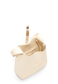 Sac en cuir crème avec une forme structurée, quincaillerie dorée et une poche zippée intérieure. Ouverture sur le dessus, texture lisse et design minimaliste.