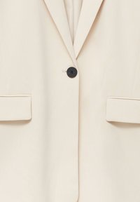 Beige blazer van glad stof, met een enkele zwarte knoop, ingesneden revers en zijzakken met omgeslagen manchetten.