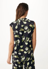 Sømløs bluse i sort stof med blomstermønster med grønne pærer og hvide blomster. Glat tekstur med en afslappet pasform.
