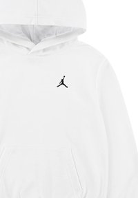 Weißer Kapuzenpullover aus Baumwolle mit einer vorderen Tasche, versehen mit einem kleinen schwarzen Jumpman-Logo auf der linken Brust. Glatte Textur.
