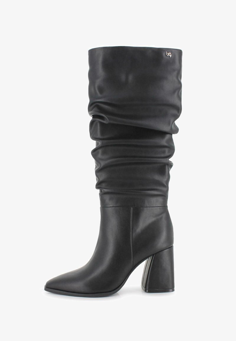 Bota de cuero negra hasta la rodilla con caña suelta, punta afilada y tacón grueso, que presenta un pequeño logo metálico cerca de la parte superior.