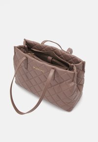 Brūns quiltota ādas somiņa ar divām garām siksnām, rāvējslēdzēja aizdari un zelta zīmolu priekšpusē. Iekšpuse ar papildu nodalījumiem.