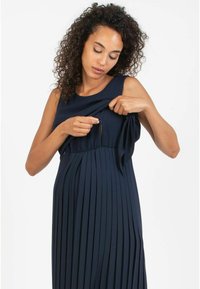 Abito plissettato blu navy con corpino aderente e dettaglio con fiocco regolabile. Presenta un accesso discreto per l'allattamento con un'apertura con zip.