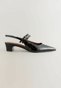 Musta kiiltonahkainen slingback-kengä, jossa on terävä kärki, kahdella säädettävällä hihnalla metallisine soljilla ja matalalla lohkopohjalla.