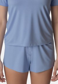 Svetle modrý loungewear set obsahující tričko s krátkým rukávem a šortky vyrobené z měkké, hladké tkaniny s volným střihem a bez viditelného kování.