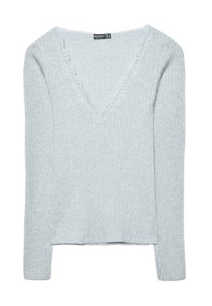 Svetlo sivi pulover z rebrasto pletenino, V-izrezom in čipkastim robom. Dolgi rokavi in rahlo krajšana dolžina. Mehka tekstura, priložnostna zasnova.