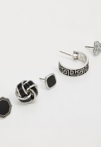 Sett med fem øreringer med sølv- og svart design. Inkluderer en knuteform, firkantede stifter, teksturerte hoops og mønstrede detaljer.