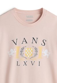 Světle růžové bavlněné tričko s velkým grafickým vzorem s textem "VANS" v černé barvě, doplněné o žluté a šedé akcenty; zahrnuje motivy lva a vavřínu.
