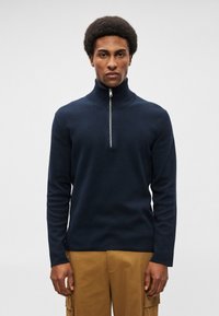 Ναυτικό μπλε, πουλόβερ με μακριά μανίκια και φερμουάρ στον λαιμό, κατασκευασμένο από απαλό πλεκτό υλικό. Διαθέτει ψηλό γιακά και διακριτική υφή.