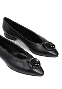 Czarne skórzane buty z ostrym noskiem, z metalowym akcentem w postaci pierścienia oraz okrągłym czarnym detalem z przodu, na niskim blokowym obcasie.