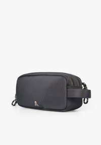 Bolso cosmético rectangular negro con superficie texturizada, dos compartimentos con cremallera y un asa lateral. Presenta un pequeño logo en la parte frontal.