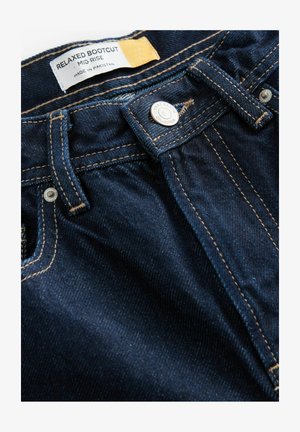 Dunkelblaue Jeans aus Denim mit einem mittelhohen Schnitt, entspannter Bootcut-Design, goldenen Nähten und einem Metallknopfverschluss. Das Etikett lautet "Hergestellt in Pakistan."