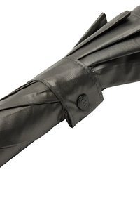 Czarna, kompaktowa parasolka z pokrywą z teksturowanej tkaniny, zabezpieczona paskiem z guzikami. Fałdowany design zwiększa elastyczność i możliwość przechowywania.