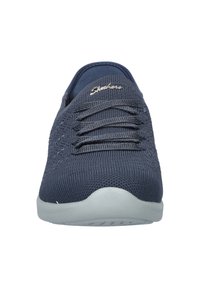 Zapatillas de deporte azul marino con parte superior de tejido trenzado, suela de goma gris lisa y cordones planos. Presenta un sutil logo de la marca en el costado.