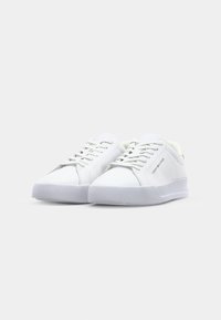 Baskets blanches avec une tige en cuir lisse, fermeture à lacets, col rembourré et semelle en caoutchouc ton sur ton. Présentent un design minimaliste et un logo embossé.