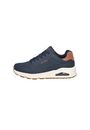 Zapatilla Skechers azul marino con suela blanca, cojín de aire visible, parche marrón en el talón y diseño con cordones sobre un fondo blanco.