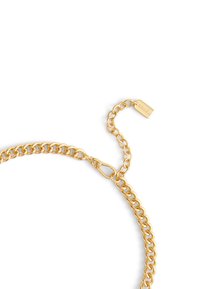 Gold-toned metal chain with interlocking links, featuring a lobster clasp and a small tag detailing the brand name. Smooth, shiny texture.