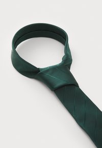 Donkergroene stropdas van glanzend materiaal, met een subtiele diagonale ribbelpatroon. Hij is in een klassieke knoop geknoopt.