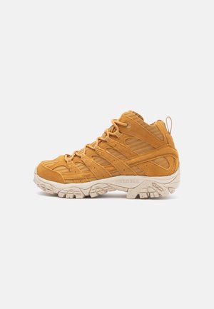 Wysokie buty trekkingowe w musztardowym zamszu, z teksturowanymi nakładkami, wzmocnionym czubkiem i kremową gumową podeszwą.