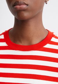 Rot-weiß gestreiftes T-Shirt mit einem runden, gerippten Ausschnitt. Weicher Stoff mit horizontalen Streifen und ordentlichem Nähdetail.