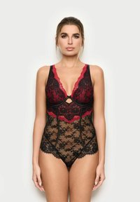 Czarny koronkowy body z czerwonymi falbaniastymi akcentami i przejrzystymi detalami, z głębokim dekoltem i skomplikowanymi kwiatowymi wzorami.