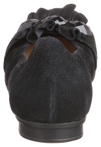 Svart mocka ballerinasko med rund tå,Volanger fram och blanka svarta detaljer. Lågt, kontrasterande gummisul.