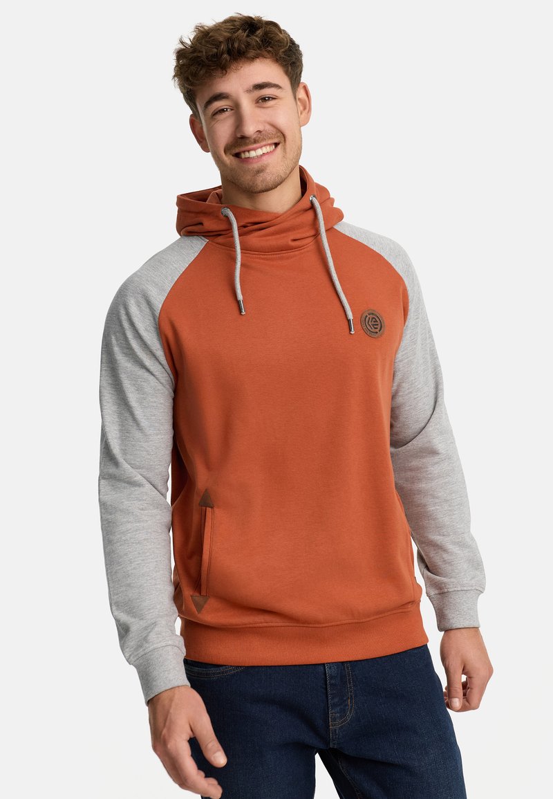 Hoody met een oranje lichaam en grijze mouwen, voorzien van een voorzak, trekkoord en logodetail op de borst. Zachte textuur.