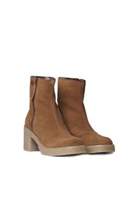 Stivali ankle in suede marrone con tacco spesso, chiusura con zip laterale e fodera interna morbida. Presentano una suola testurizzata e scanalata.