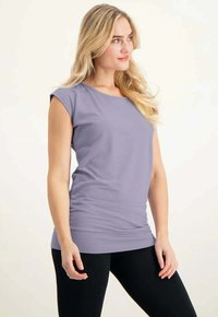 Hellblaues, kurzärmliges Oberteil mit rundem Ausschnitt, glatter Textur und taillierter Silhouette, kombiniert mit schwarzen Leggings.
