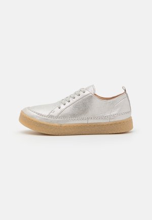 Chaussures à lacets métalliques argentées avec un dessus texturé, un bout rond et une semelle en caoutchouc beige clair. Design minimaliste avec une boucle à l'arrière.