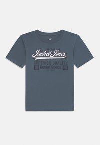 T-shirt en coton bleu à manches courtes et col rond. Présente un graphisme en texte blanc avec le nom de la marque et "Qualité Supérieure" en imprimé foncé.