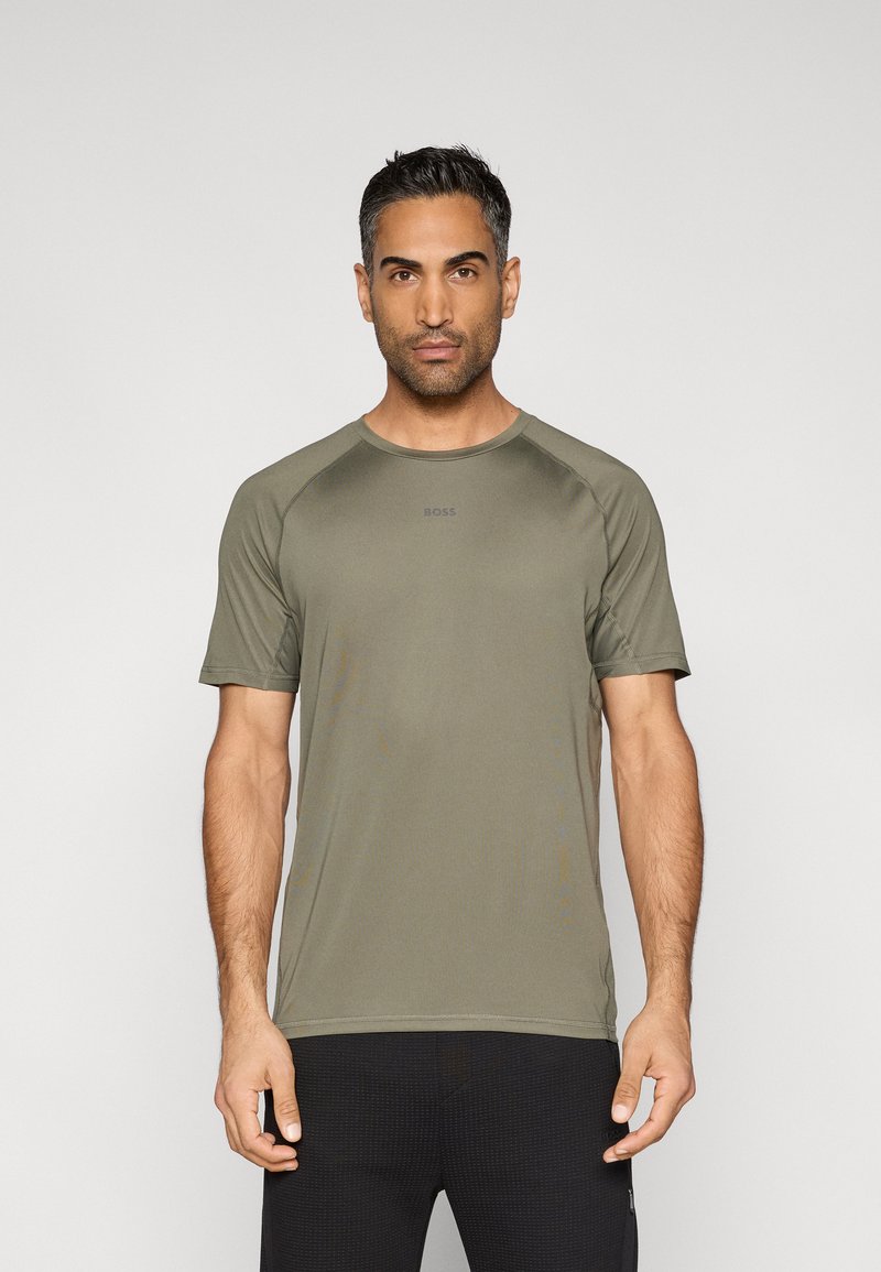 Oliwkowa zielona sportowa koszulka z krótkim rękawem, okrągłym dekoltem i raglanowymi rękawami. Na piersi subtelne logo, gładka faktura.