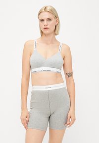 Gray cotton bralette with a V-neck and logo straps, paired with matching gray shorts featuring a logo waistband. Smooth texture.
