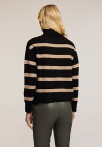 Černý a béžový pruhovaný svetr s vysokým límcem, strukturovaným pleteným materiálem, zkráceným střihem a žebrovanými manžetami. Nosit s zelenými koženými kalhotami.