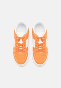 Baskets orange avec des accents blancs, dotées d'une tige synthétique lisse, d'un bout rond et de lacets plats sur une semelle en caoutchouc blanche.