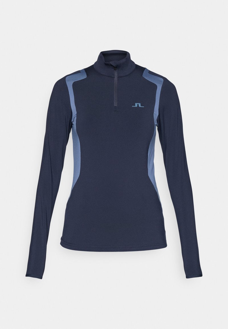 Haut à manches longues bleu marine avec un col zippé mi-hauteur. Présente des panneaux latéraux bleu clair et un petit logo sur la poitrine. Matériel lisse et extensible.