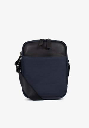 Kompaktowa granatowa torba na ramię z czarnym skórzanym panelem górnym, podwójnym zamkiem błyskawicznym i regulowanym czarnym paskiem z tkaniny.