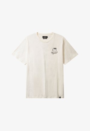 Camiseta de manga corta en algodón color crema con un dibujo de una taza de caricatura negra y un personaje en el lado izquierdo del pecho. Textura suave, ajuste relajado.