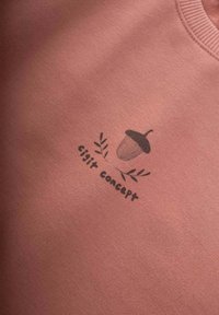 Ružová mikina s grafikou žaludu a listov s potlačou textu "gigit concept" pod ním. Hladká textúra látky.